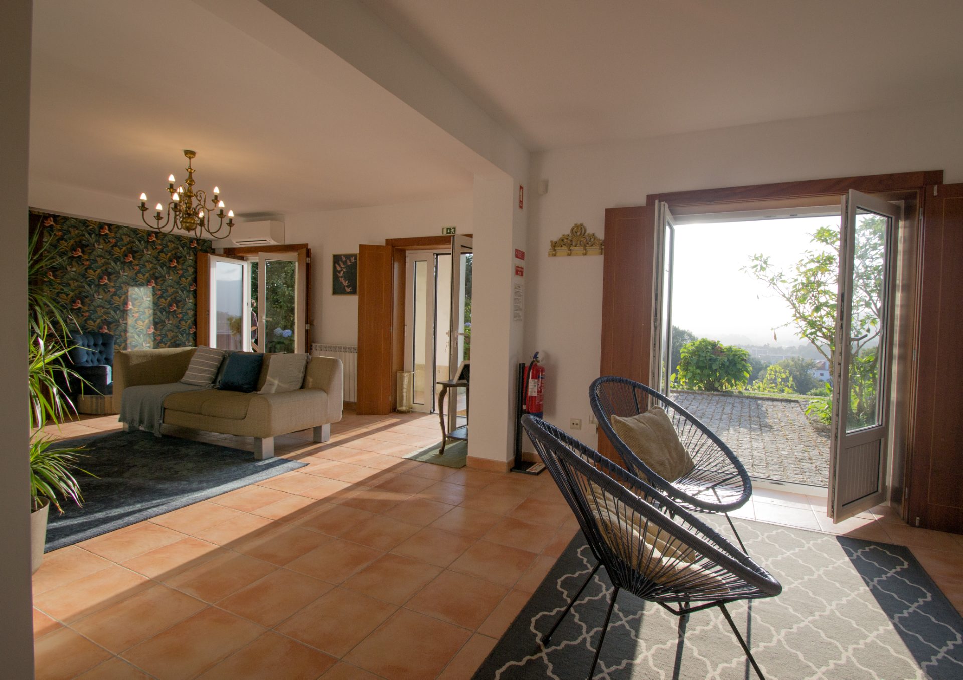 Entrada e sala com cadeiras Acapulco e portas abertas