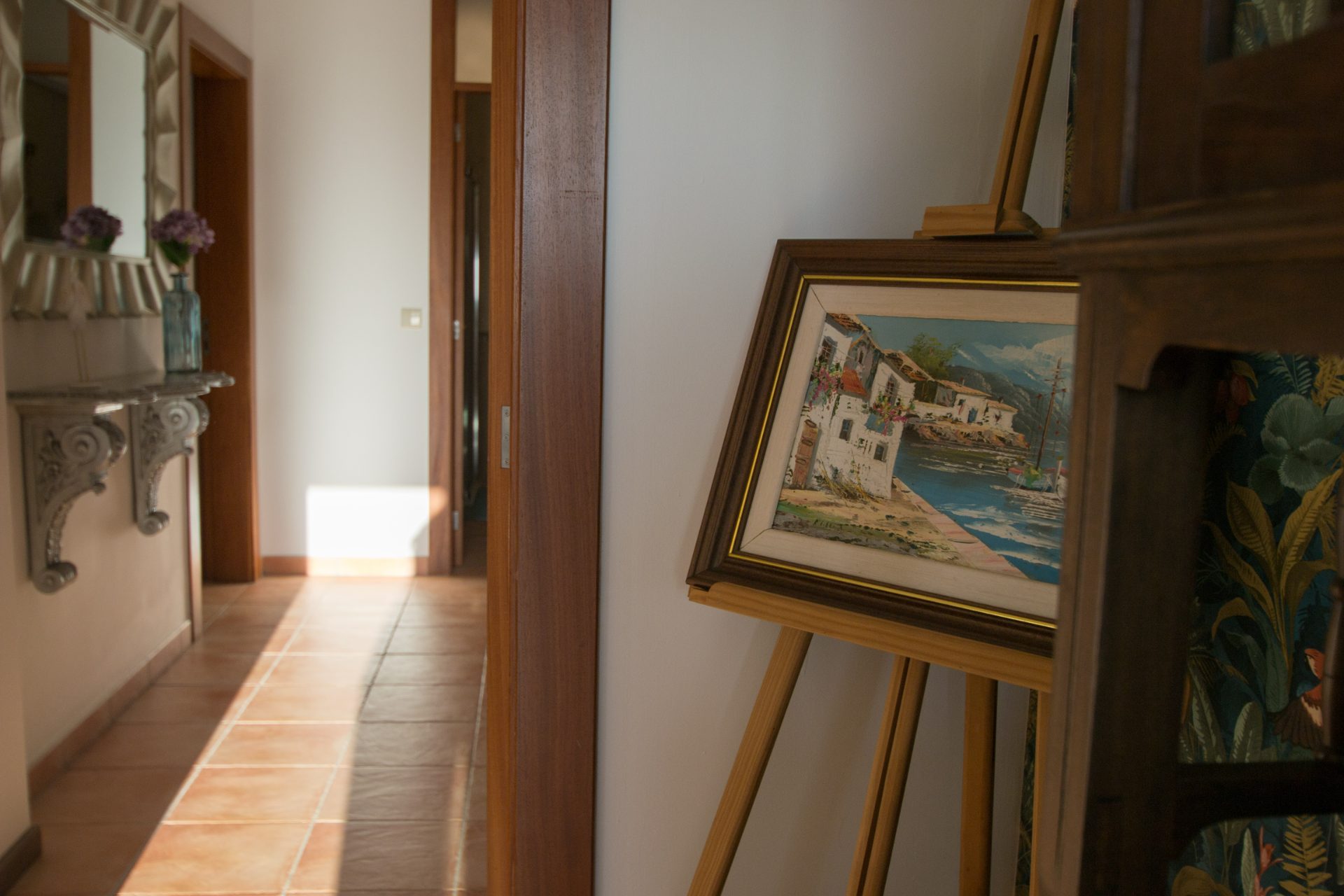 Corredor com quadro em cavalete e espelho