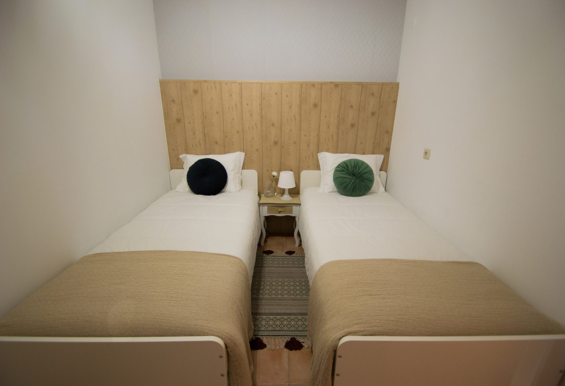 Quarto pequeno com duas camas individuais e cabeceira em madeira