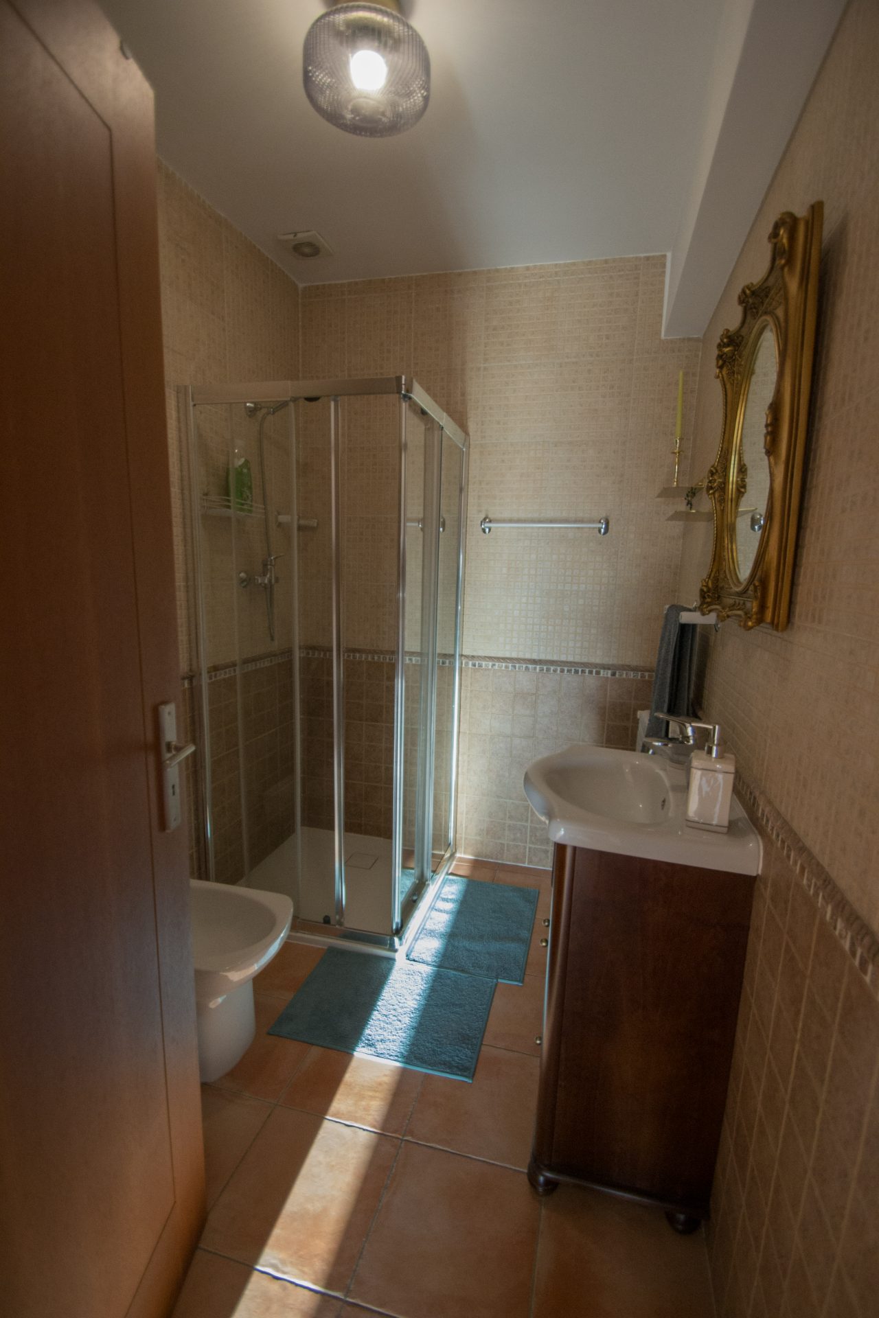 Casa de banho com duche e espelho dourado